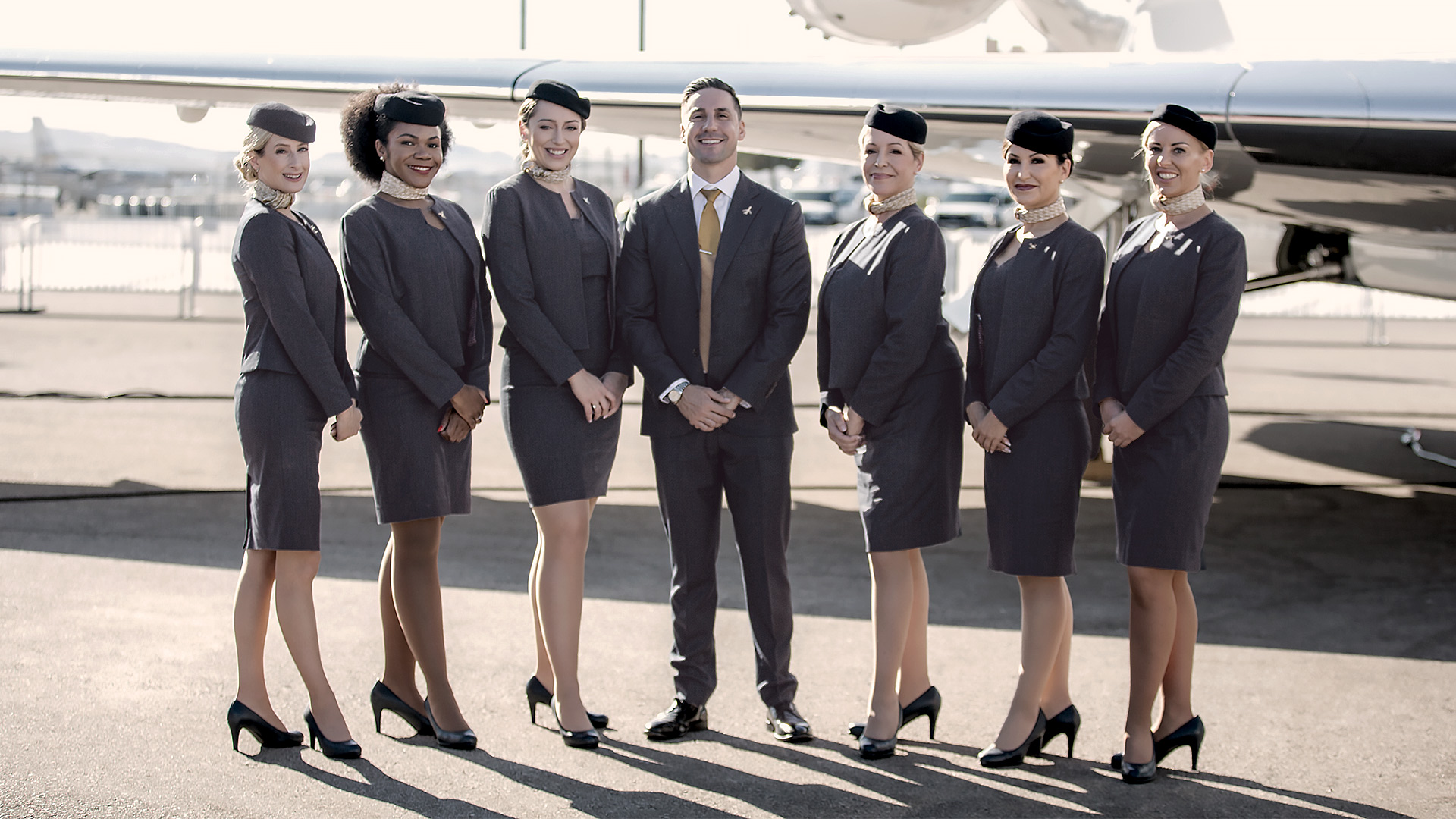 Group of flight attendants standing together in front of an aircraft