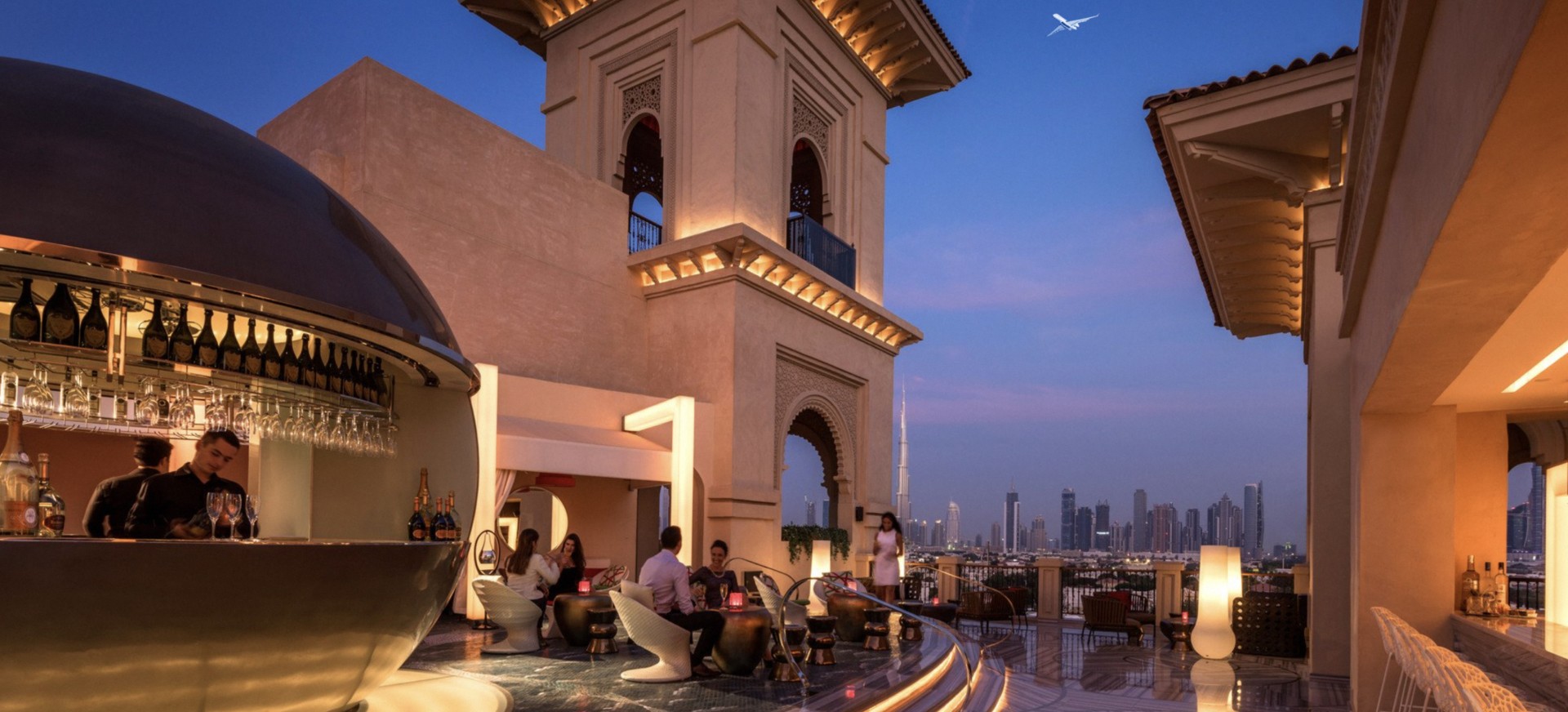 Rooftop bar in Dubai at night with plane flying in sky