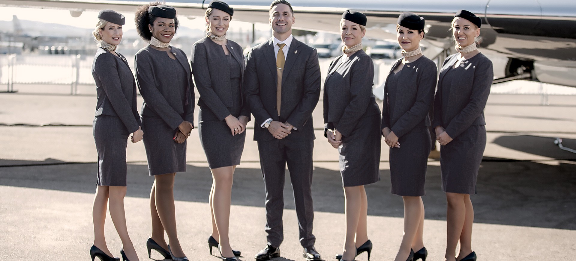 Group of flight attendants standing together in front of an aircraft